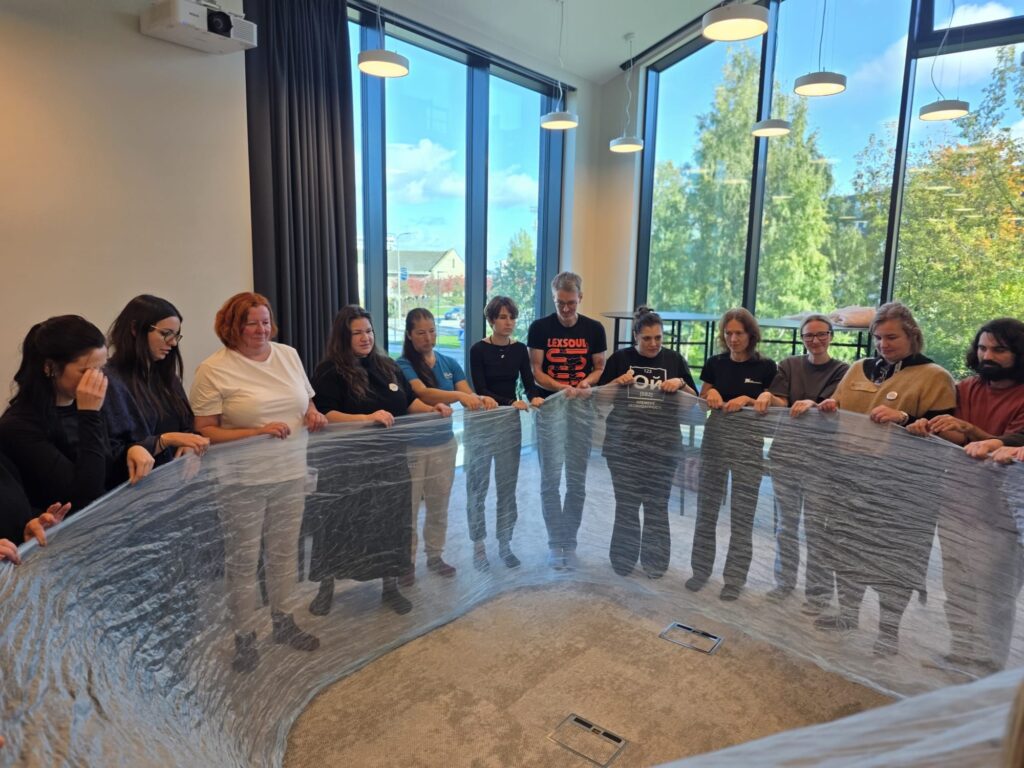 Participants working with a shared fabric during a playback theatre workshop in Tallinn